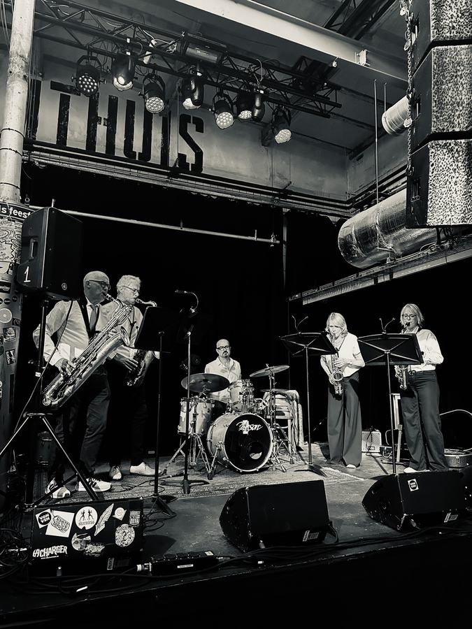 Saxofoonband speelt op het podium in zwart-wit