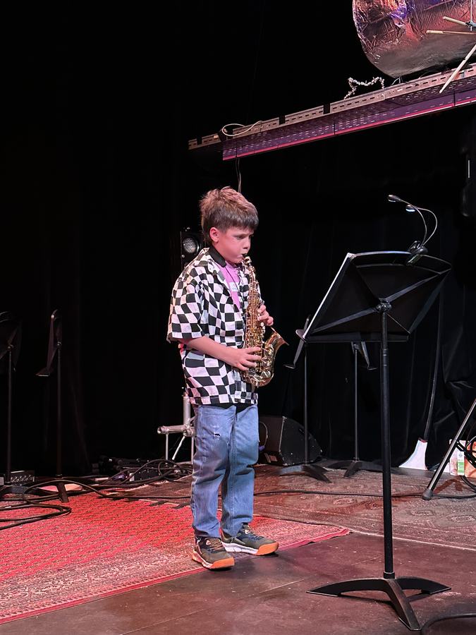 Jonge leerling speelt saxofoon op het podium