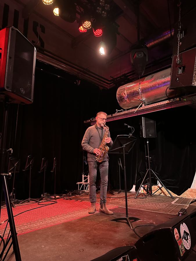 Saxofonist speelt solo op een podium met rood licht