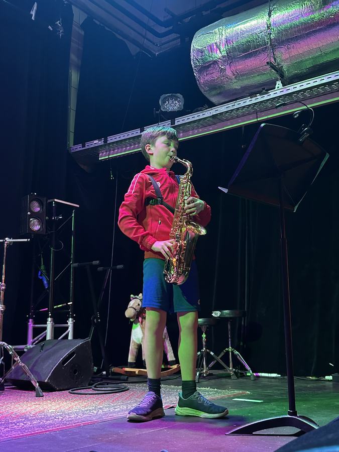 Jonge leerling speelt saxofoon op een podium